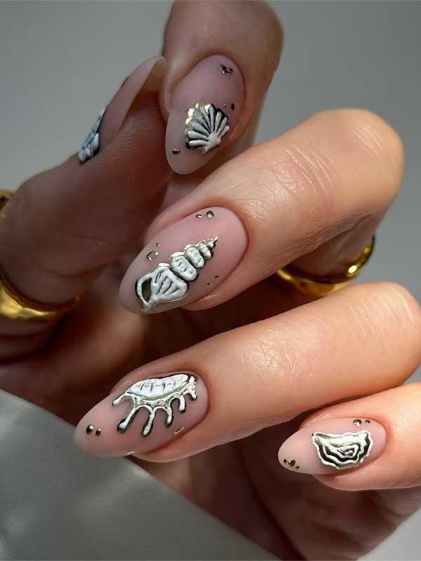 Elegant seashell nail art featuring 3D designs in pearly white and metallic accents on a soft nude background. Elegant seashell nail art featuring 3D designs in pearly white and metallic accents on a soft nude background.