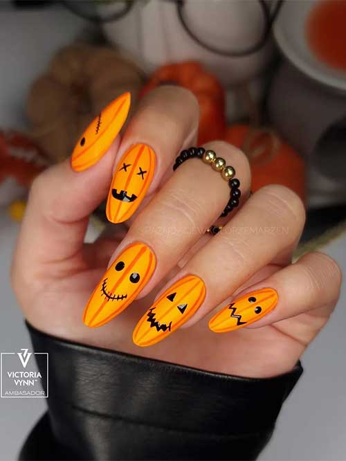 Halloween pumpkin nails long using matte yellow base color and orange pumpkin strips with black eyes and mouths
