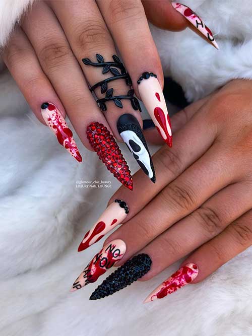 Long Halloween nails stiletto scary features blood splatter nail art over nude nails, red and black rhinestones