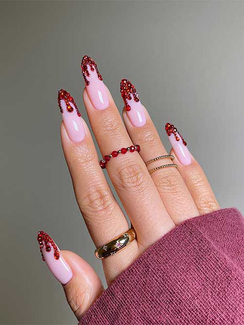 Long almond shaped red rhinestone blood drip nails over nude pink base color