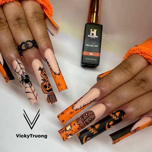 Long matte orange and black Halloween nails with stitch nail art, pumpkins, ghosts, and cobwebs.