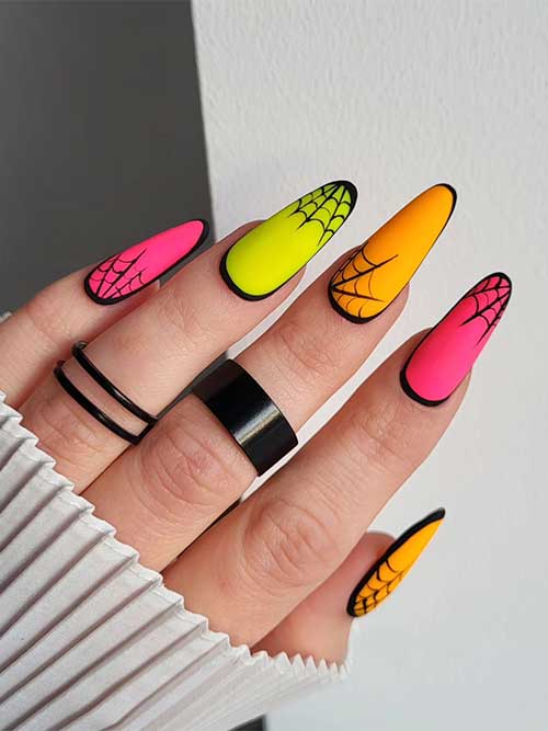 Multicolored bright neon Halloween nails feature pink, orange, and yellow nails with black cobwebs and black outlines.