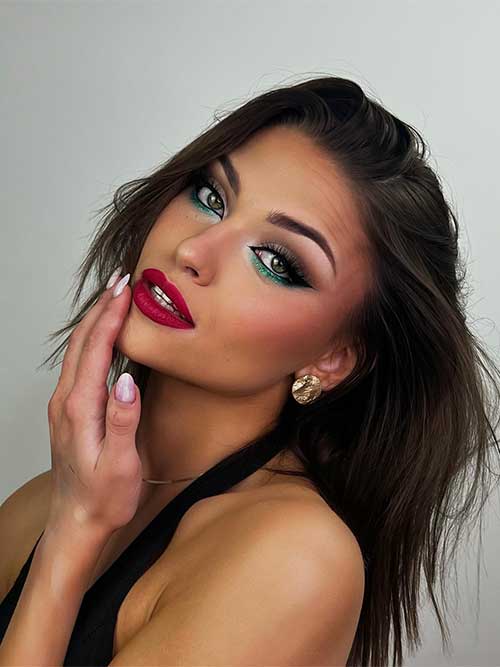 Christmas makeup look features smoky eyes, black winged eyeliner, and glitter emerald green eyeshadow on the lower lash
