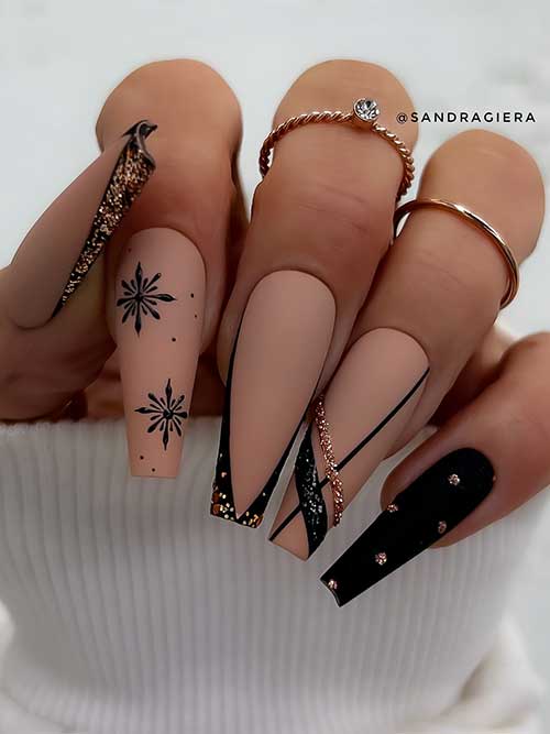 Classy matte nude nails with black design feature black snowflakes and two V-shaped black French tip nails with gold glitter