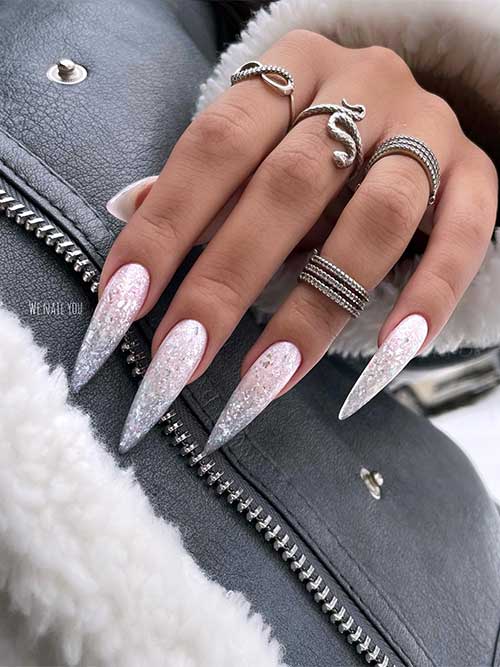 Dazzling long stiletto-shaped nude and silver glitter ombre New Year’s nails adorned with a touch of silver foil flakes