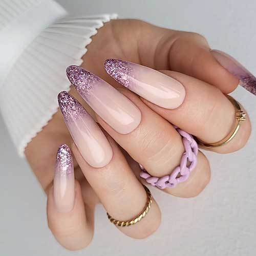 Festive long almond-shaped nude New Year's nails with pink aurora glitter on the nail tips
