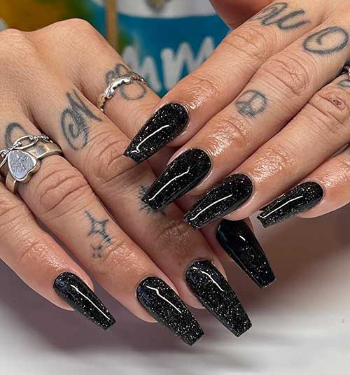 Long glossy coffin black nails with a touch of silver glitter that suit New Year’s Eve
