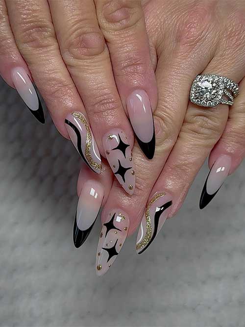 Long nude clear base color with black French tips and an accent nail adorned with black, gold glitter, and white swirls