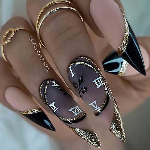 Long stiletto-shaped black and gold glitter New Year’s nails with clock nail art on the finger and middle accent nails