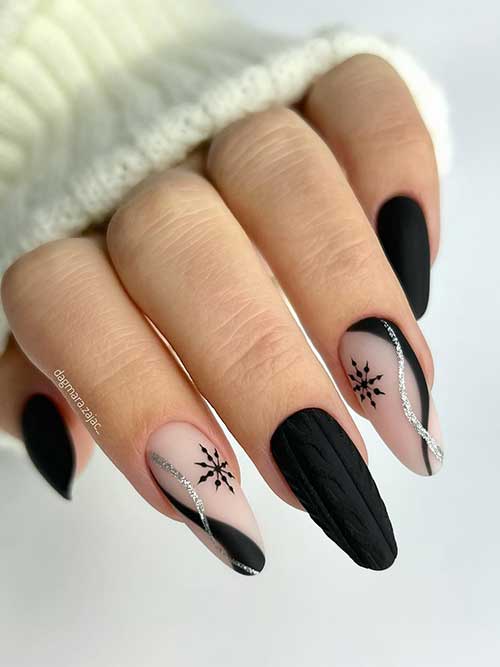 Matte black nails with two nude accent nails adorned with black snowflakes in addition to black and silver glitter swirls