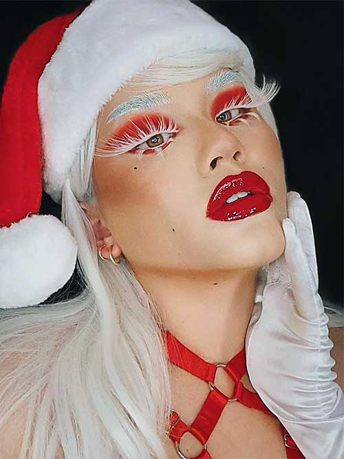 Mrs. Claus's makeup look features red eyeshadows, glossy red lips, white long lashes, and white eyebrows