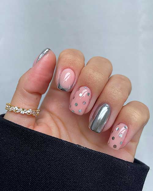  Nude and silver chrome New Year’s nails feature two French tip nails and two nude nails with hexagonal polka dot glitters