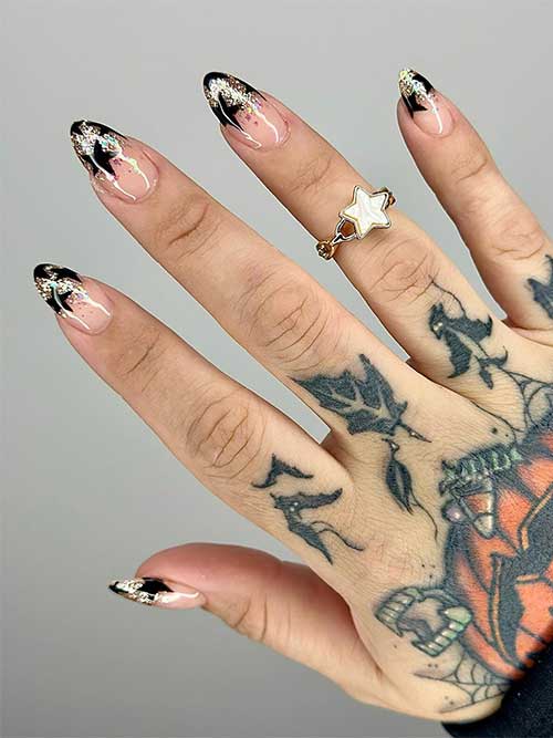 Short almond-shaped nude New Year's nails with gold glitter on the nail tips adorned with black stars