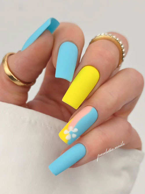 Matte light blue nails with yellow accents and a white flower design, offering a playful and elegant modern manicure. Matte light blue nails with yellow accents and a white flower design, offering a playful and elegant modern manicure.