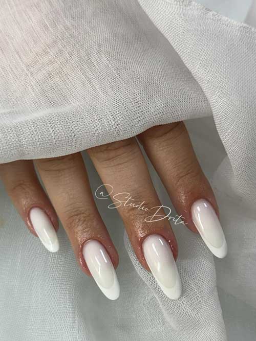 Almond-shaped white nails with a milky base and blended white tips, showcasing a chic and polished French manicure style. Almond-shaped white nails with a milky base and blended white tips, showcasing a chic and polished French manicure style.