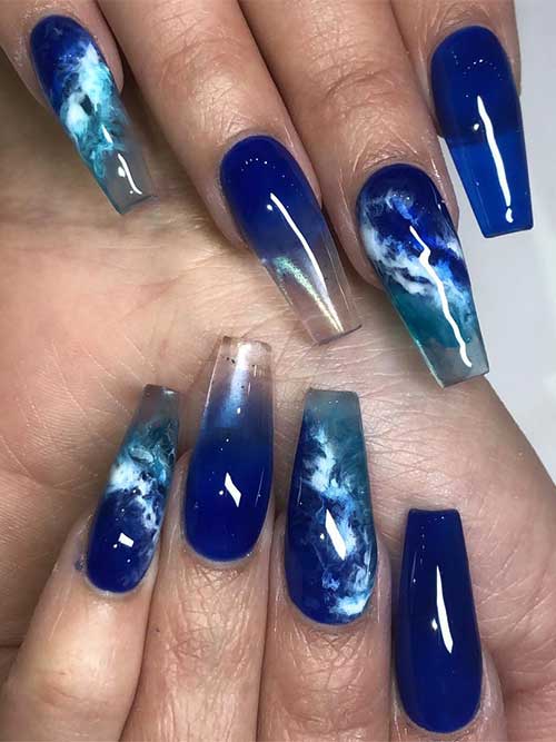 Bold coffin-shaped ocean nails featuring deep blue hues and wave swirls, offering a dramatic and elegant seaside look Bold coffin-shaped ocean nails featuring deep blue hues and wave swirls, offering a dramatic and elegant seaside look