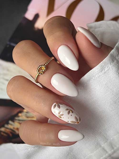 Elegant almond-shaped white nails with a high-gloss finish, adorned with floral designs and gold foil for a chic, understated style. Elegant almond-shaped white nails with a high-gloss finish, adorned with floral designs and gold foil for a chic, understated style.