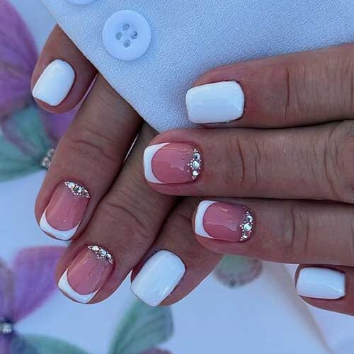Short white nails with French tips and silver rhinestones, offering a chic and minimalist touch of glam.