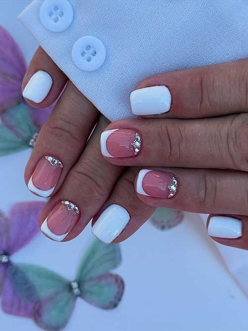 Short white nails with French tips and silver rhinestones, offering a chic and minimalist touch of glam. Short white nails with French tips and silver rhinestones, offering a chic and minimalist touch of glam.